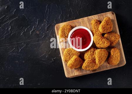 Pepite di pollo con salsa barbecue su sfondo nero, scattate dall'alto con un posto per il testo. Snack croccanti, fotografia gastronomica Foto Stock