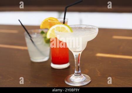 Bicchieri da cocktail su sfondo di legno. Margarita, tequila sunrise, mojito Foto Stock