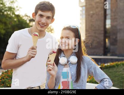 Bella giovane coppia adolescente in città vicino all'università con gelato dopo aver studiato e divertendosi insieme ridendo e sorridendo Foto Stock