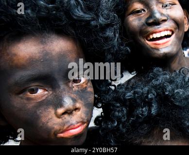 Ragazzi thailandesi con un corpo dipinto di nero e una parrucca afro durante un festival sulla strada Charoennakorn a Bangkok, Thailandia. Foto Stock