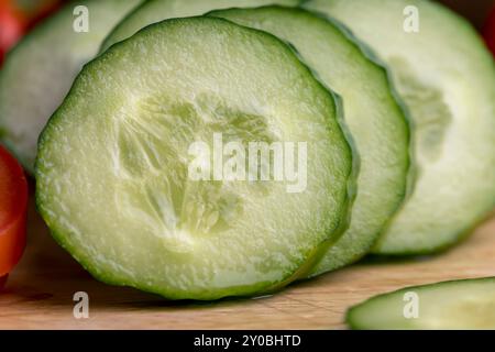 Cetriolo lungo verde a fette durante la preparazione dell'insalata, preparazione dell'insalata con verdure tagliate a pezzetti di cetrioli verdi Foto Stock