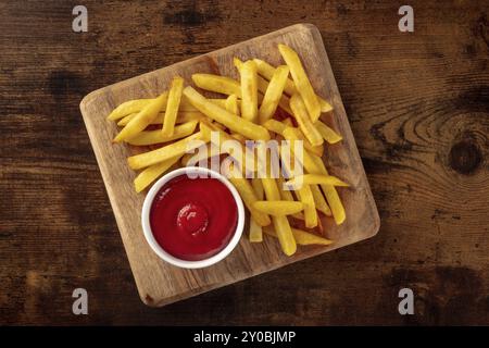 Patatine fritte, snack di patate con ketchup, fast food su un tavolo di legno, piatto sopra la testa di tiro Foto Stock