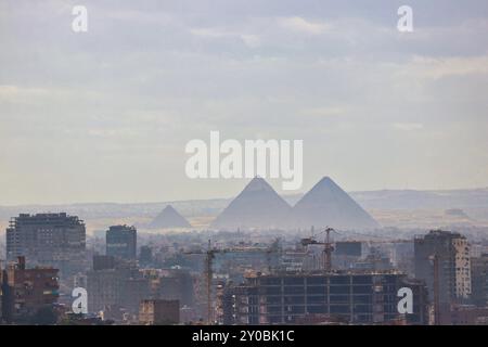 Le grandi Piramidi di Giza incombe sulla moderna e polverosa megapoli del Cairo in questa spettacolare vista panoramica a lungo raggio dalla cima della Cittadella di Saladino nel Cairo islamico, in Egitto Foto Stock