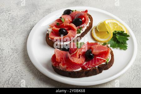 Panini con formaggio spalmabile, salmone salmone, affumicato a freddo, pane di grano, vista dall'alto, colazione, limone e prezzemolo, niente gente Foto Stock