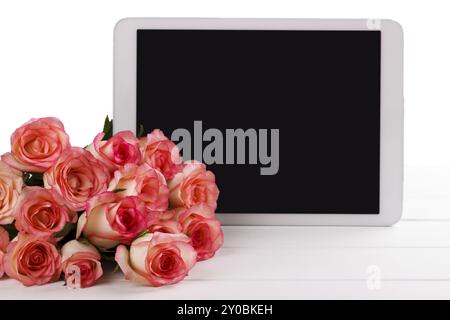 Tablet e bouquet di rose rosa su sfondo bianco. Spazio per il testo Foto Stock