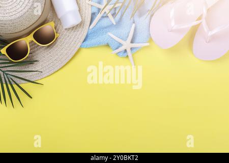 Accessori da spiaggia su sfondo giallo, occhiali da sole, crema solare, infradito, asciugamano e cappello, concetto di vacanza estiva, spazio per la copia Foto Stock