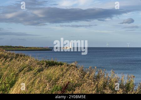 Costa del Mare del Nord con St. Mary's Faro e delle turbine a vento, visto da Whitley Bay a Tyne and Wear, England, Regno Unito Foto Stock