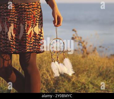 Brunette donna con capelli lunghi tenendo dream catcher nelle sue mani Foto Stock
