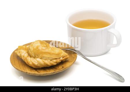 Deliziosa pasta di curry in un piatto di legno e una tazza di tè su sfondo bianco Foto Stock