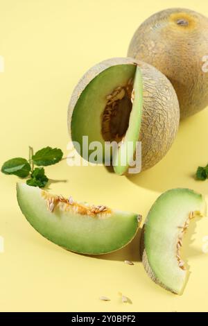 Melone verde cantaloupe a fette su tavolo giallo Foto Stock