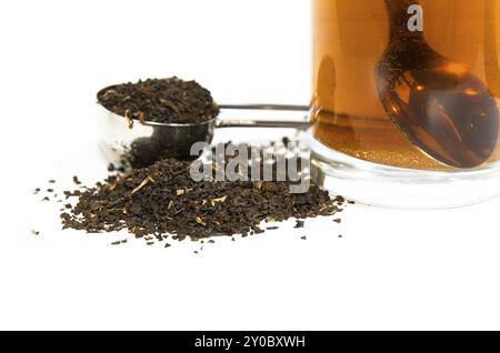 Foglie di tè nel misurino e un bicchiere di tè. Tealeaves nel misurino e un bicchiere di tè Foto Stock