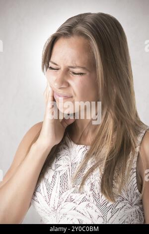 Donna con un mal di denti isolati in grigio Foto Stock