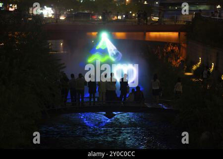 Una silhouette di turisti che guardano lo spettacolo di luci laser Cheonggyecheon ogni ora nel centro di Seoul, Corea Foto Stock