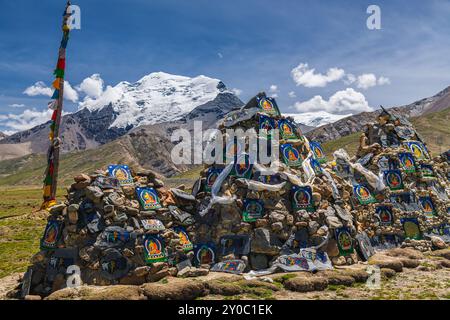 Piramide di bandiere di preghiera di fronte alle montagne innevate dell'Himalaya al passo di Lalung la, 5050 m di altitudine sulla Friendship Highway tra Lhasa Foto Stock