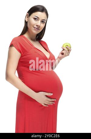 Felice giovane donna incinta in abito rosso di toccare la sua pancia e azienda apple Foto Stock