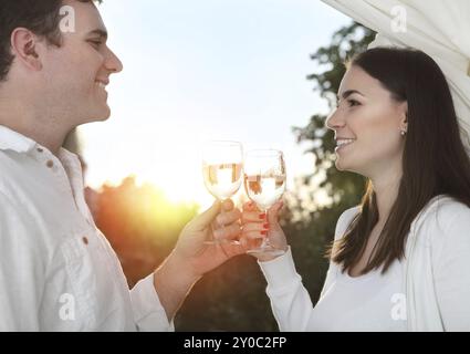 Giovane coppia felice che si gusta un bicchiere di vino bianco in giardino Foto Stock