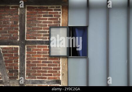 Vecchio e nuovo (finestra in una facciata di vetro accanto a un muro in legno) Foto Stock
