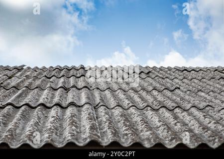 Lenzuola di amianto grigie su un tetto di casa, vista panoramica con cielo blu Foto Stock