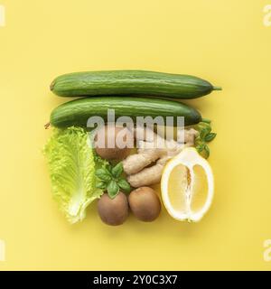 Cibo sano e organico flay concetto su sfondo giallo. Una piazza fatta di verdure e frutta differenti come lea di limone, zenzero, insalata di lattuga Foto Stock