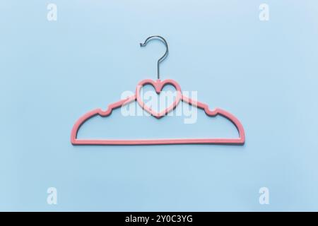 Black Friday o concetto di industria dell'abbigliamento su sfondo blu piatto con un singolo appendiabiti rosa con forma a cuore su appendiabiti Foto Stock
