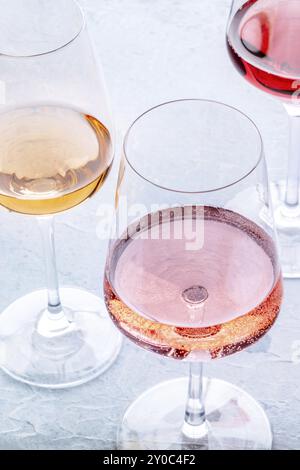 Bicchieri da vino a una degustazione. Rosa, vino rosso e bianco, bevande su un tavolo in un'azienda vinicola. Colori diversi del vino, fotografia gastronomica Foto Stock