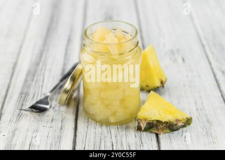 Ananas tritato fresco (conservato) su un vecchio e rustico tavolo in legno, messa a fuoco selettiva, foto ravvicinata Foto Stock