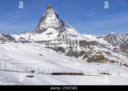 Zermatt, Svizzera, 12 aprile 2017: Un treno rosso di fronte alla montagna innevata del Cervino, Europa Foto Stock