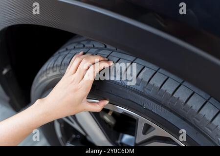 Mano donna che controlla la pressione dell'aria pneumatico per auto. Primo piano di una donna irriconoscibile che controlla lo stato degli pneumatici della sua auto. Concetto di guida e guida Foto Stock