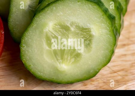 Cetriolo lungo verde a fette durante la preparazione dell'insalata, preparazione dell'insalata con verdure tagliate a pezzetti di cetrioli verdi Foto Stock