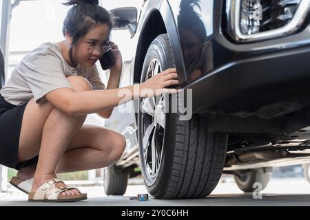 Il meccanico controlla la pressione degli pneumatici in una ruota di un veicolo. Dare potere alle donne che lavorano in un'officina di riparazione di auto moderna e pulita. Gli specialisti gonfiano la ruota dopo Foto Stock