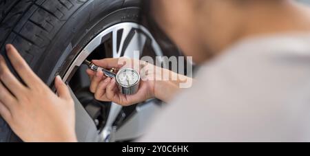 Manometro per pneumatici : manometro di tenuta manuale che controlla la pressione dell'aria per pneumatici per auto. Guida sicura. Meccanico al lavoro in officina, pressione pneumatici Foto Stock