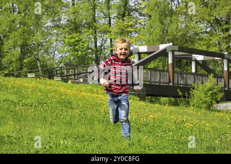 Un ragazzo felice attraversa un prato estivo Foto Stock