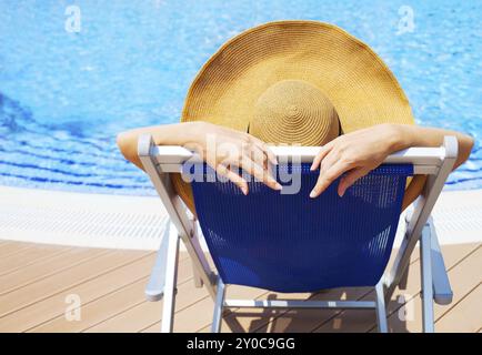 Giovane e bella donna che indossa hat giacente sulla sdraio da piscina Foto Stock