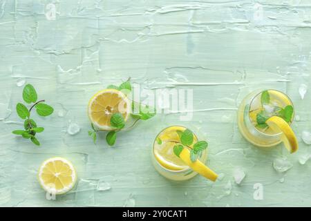 Limonata con menta. Bere acqua di limone con ghiaccio. Due bicchieri e limoni su sfondo blu, scattati dall'alto con spazio di copia. Disintossicazione delle bevande. Fresco Foto Stock