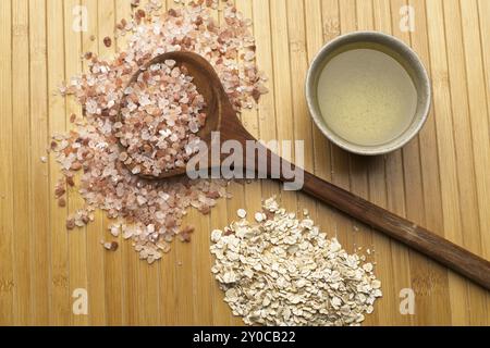 Una foto da studio a spiovente di una pila di sale marino dell'himalaya con un cucchiaio, una pila di avena secca e una piccola ciotola con olio d'oliva Foto Stock