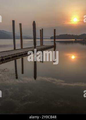 Il sole sorge abbastanza al mattino da proiettare un bagliore colorato sul lago Chatcolet nell'Idaho settentrionale Foto Stock