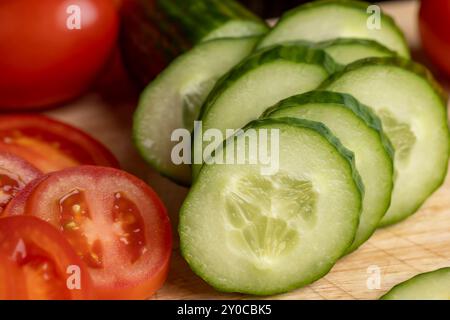 Cetriolo lungo verde a fette durante la preparazione dell'insalata, preparazione dell'insalata con verdure tagliate a pezzetti di cetrioli verdi Foto Stock