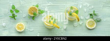 Limonata con panorama alla menta. Bere acqua al limone con ghiaccio. Due bicchieri e limoni su sfondo blu, shot piatto sopra la testa. Bevanda disintossicante. Fresco ho Foto Stock