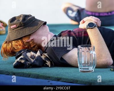 Il giovane stanco dorme, bicchiere vuoto, cappello sopra la testa Foto Stock