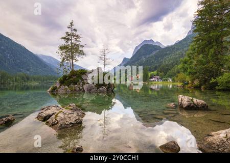 Hintersee con rocce e alberi in primo piano, circondato da montagne dopo il tramonto con un cielo nuvoloso, Ramsau, il Parco Nazionale di Berchtesgaden, Foto Stock