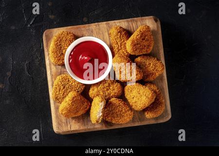 Pepite di pollo su sfondo nero, colpo piatto sospeso. Un antipasto croccante in un ristorante, un piatto fast food, fotografia di cibo, fotografia di cibo Foto Stock