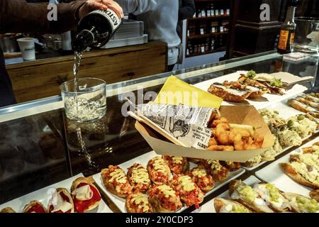 Madrid, Spagna, 27 dicembre 2019: Tapas tradizionali e vino in un mercato alimentare di Madrid, versare vino in un bicchiere, Europa Foto Stock