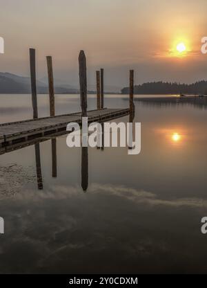 Il sole sorge abbastanza al mattino da proiettare un bagliore colorato sul lago Chatcolet nell'Idaho settentrionale Foto Stock