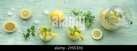 Limonata con panorama alla menta. Bevanda acquosa al limone con ghiaccio, due bicchieri e una caraffa su sfondo blu, shot piatto sopra la testa. Bevanda disintossicante. Fresco Foto Stock