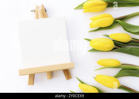 Piatto con fiori di tulipano gialli e cornice vuota su sfondo bianco. Biglietto d'auguri per Pasqua, Festa delle madri, Giornata internazionale delle donne Foto Stock
