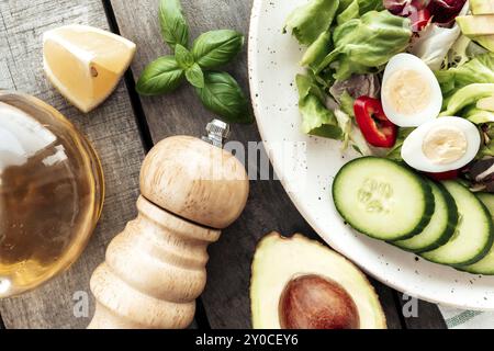 Concetto sano di mangiare piatto posato. Dieta mediterranea, piatto con foglie di insalata di lattuga, uova di quaglia, metà avocado con nocciolo, fette di cetriolo, pepe, b Foto Stock