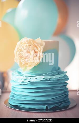 Torta a strati decorata con fondente blu e delizioso fiore commestibile giallo servito a tavola per il compleanno Foto Stock