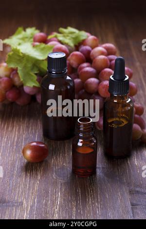 Bottiglia piccola con olio di semi d'uva su un tavolo di legno, messa a fuoco selettiva Foto Stock