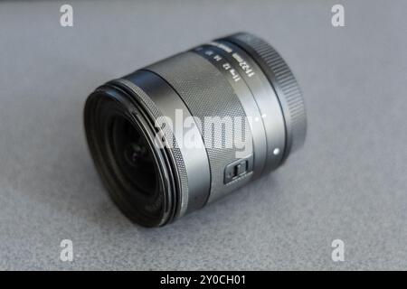 Obiettivo grandangolare piccolo di 11-22 mm, appoggiato a terra. Lente di piccole dimensioni senza copriobiettivo. Abbigliamento fotografico con obiettivo zoom. Foto Stock