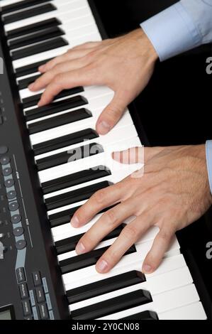 Primo piano di mani maschili che suonano il pianoforte in studio Foto Stock